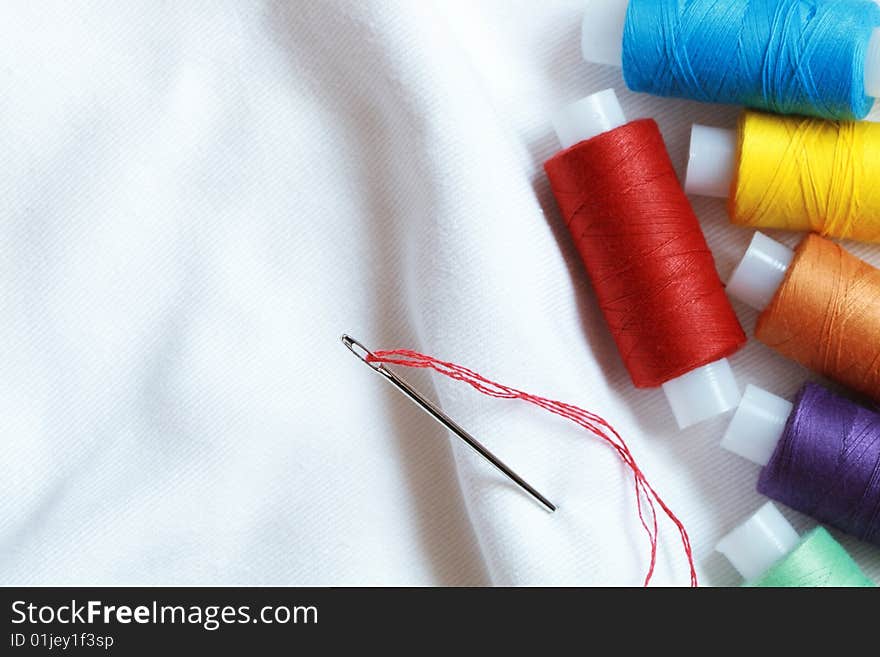 Spools of variegated thread lying on background with white cloth. Spools of variegated thread lying on background with white cloth