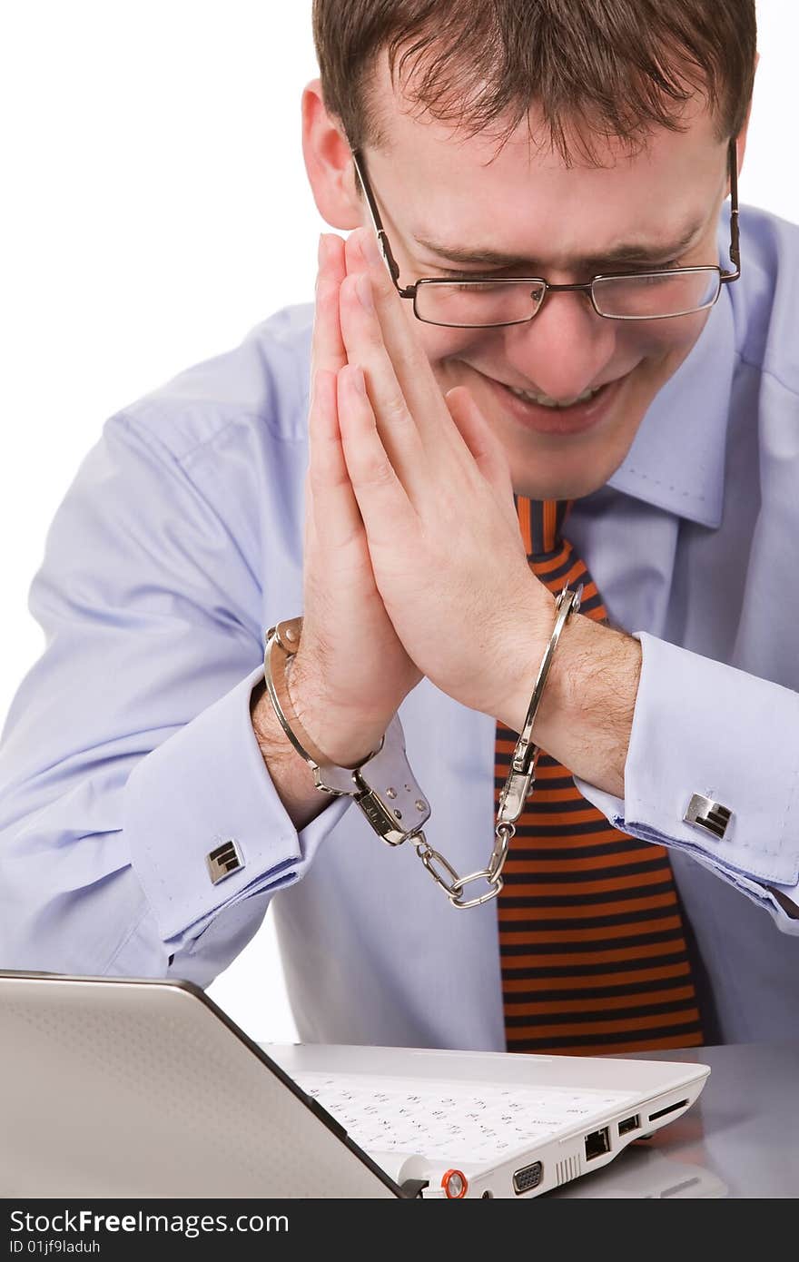 Handsome young businessman bound to laptop with handcuffs. Handsome young businessman bound to laptop with handcuffs