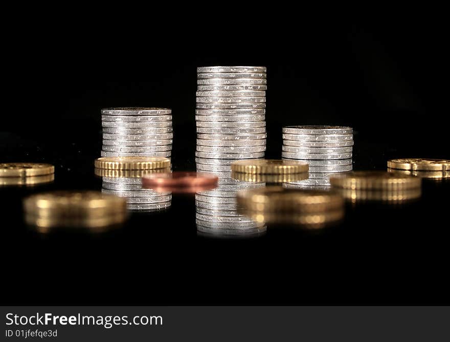 Coins over black background. Reflection in the table.