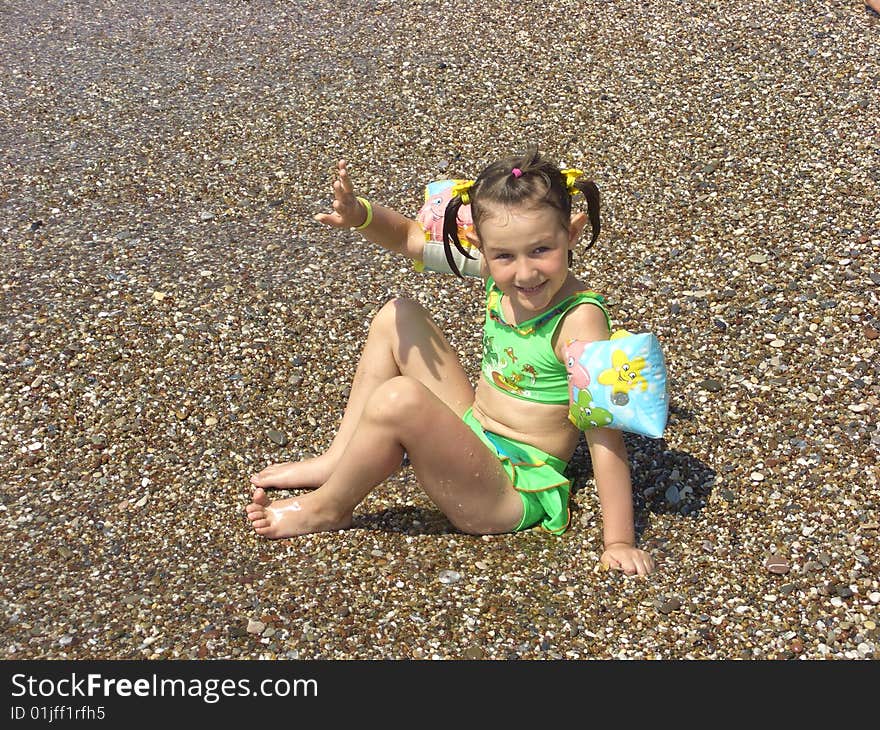 A girl in a green swimming suit plays the bank near water. A girl in a green swimming suit plays the bank near water.