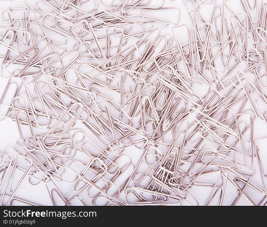 Heap of steel grey paperclips on white background