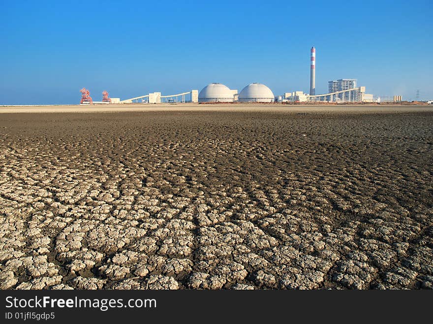 Cracks of dried Seabed backgrounded by a power Plant. Cracks of dried Seabed backgrounded by a power Plant