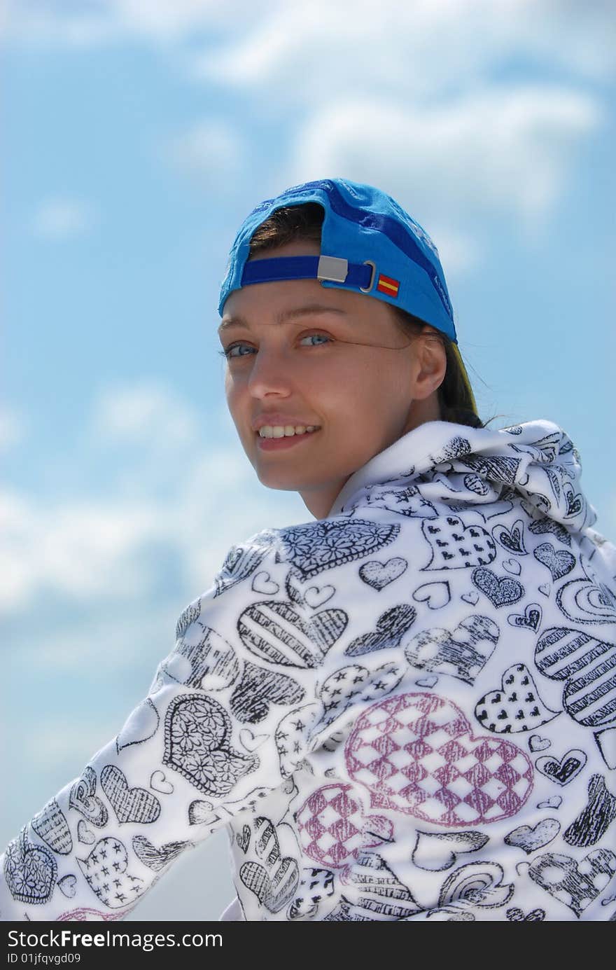 Woman in baseball cap, sitting back on a background of blue sky