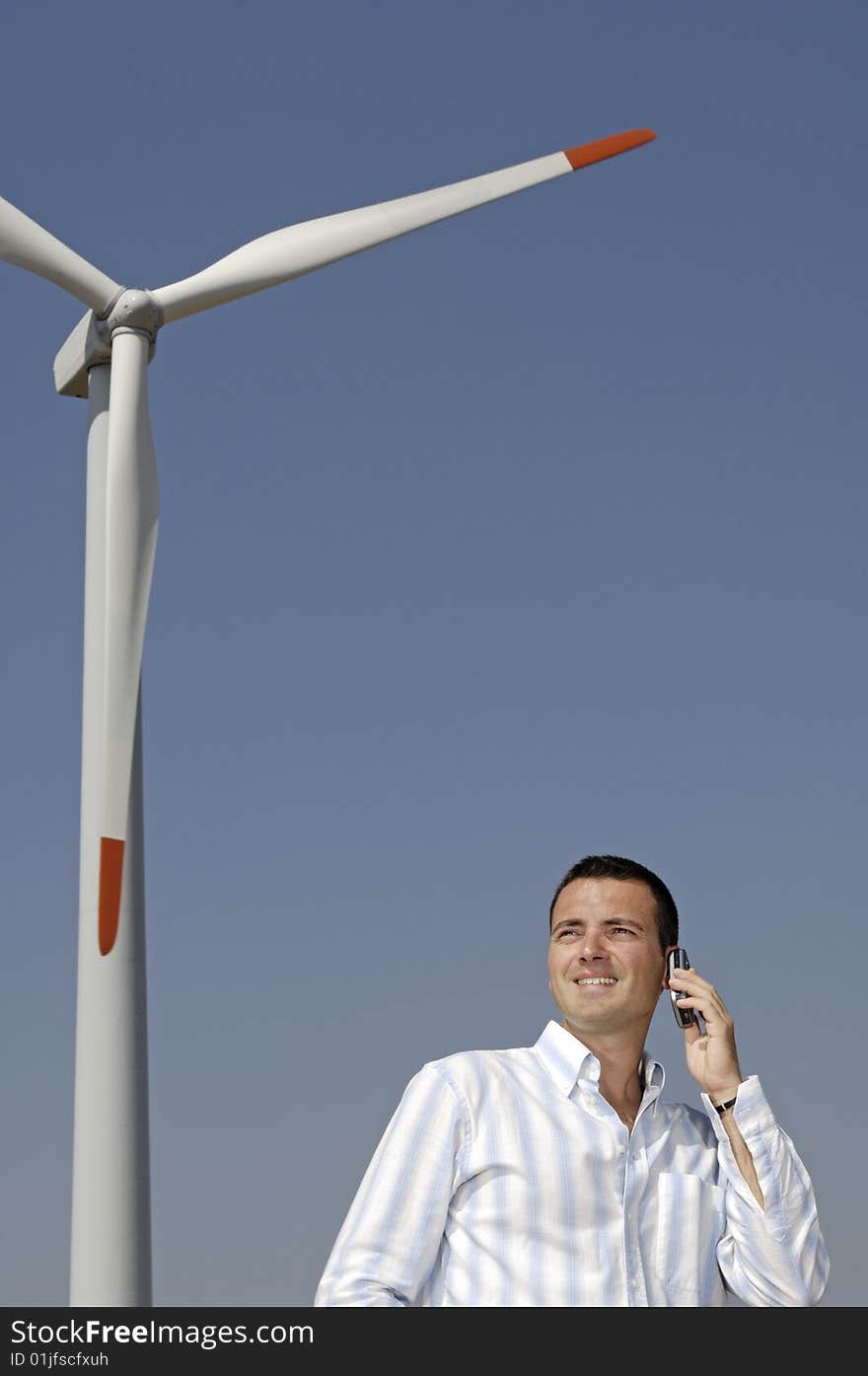 Man and wind turbines; young adult uses cellular with wind turbines in background