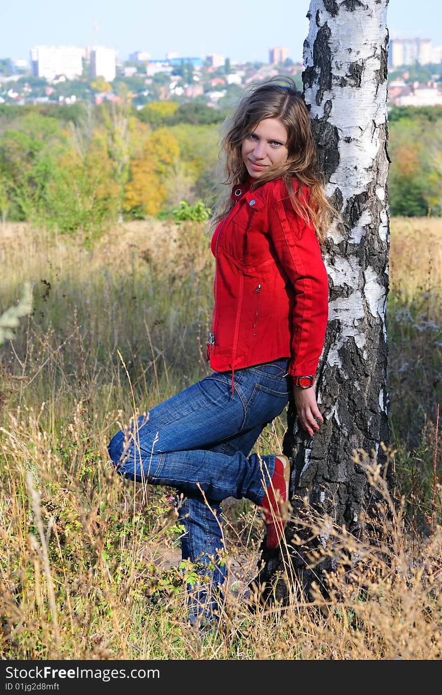 The girl leans against a birch and looks in the cam. The girl leans against a birch and looks in the cam