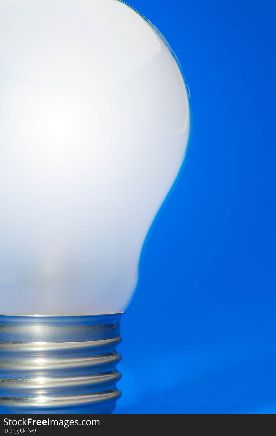 Illuminated light bulb on blue studio lit background