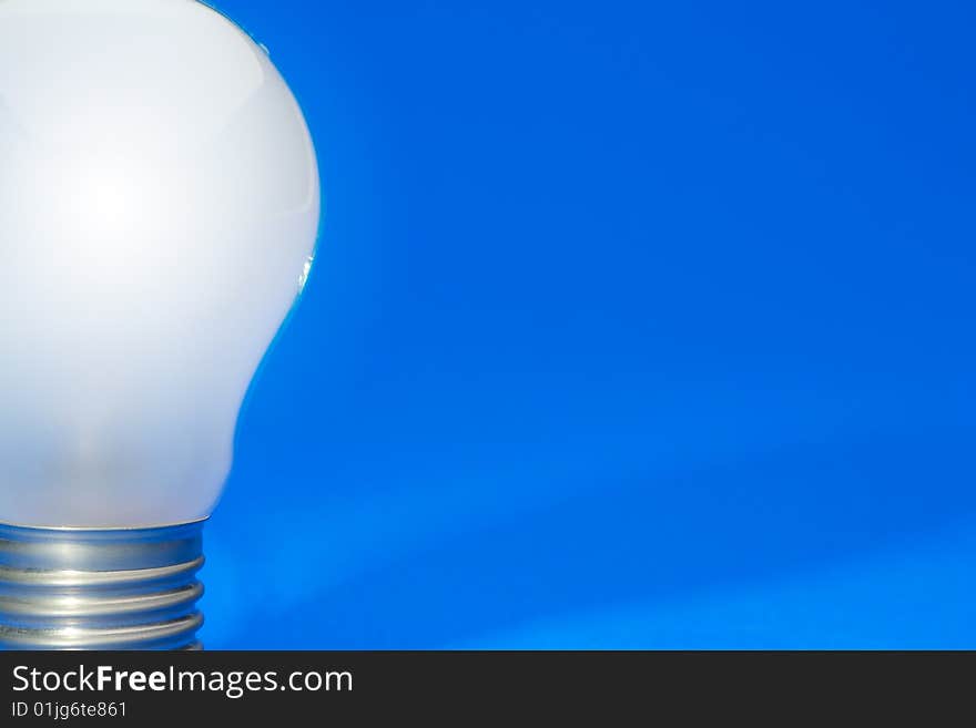 Illuminated light bulb on blue studio lit background