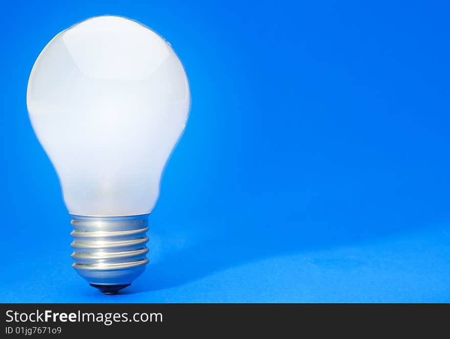 Illuminated light bulb on blue studio lit background