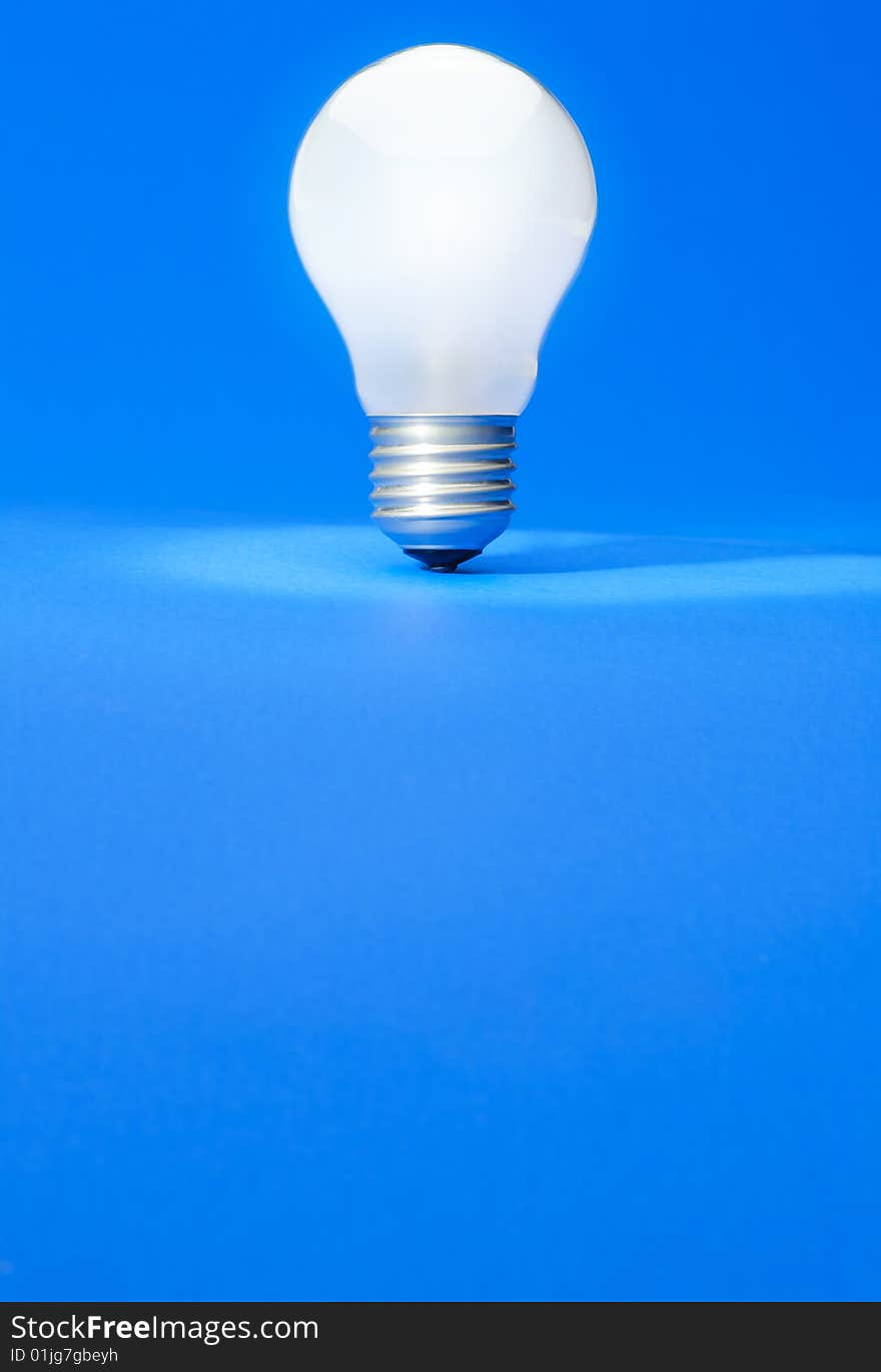 Illuminated light bulb on blue studio lit background