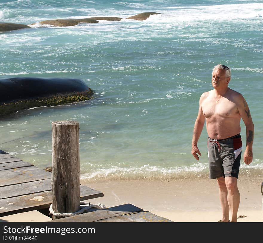 This senior man is enjoying a stroll on the beach with the ocean tide rolling in. This senior man is enjoying a stroll on the beach with the ocean tide rolling in.