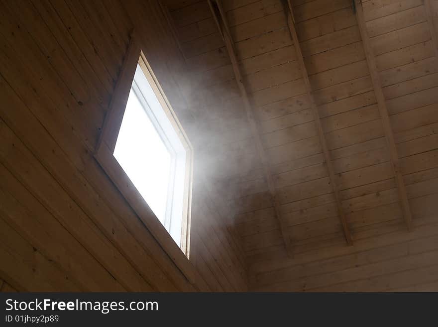 Light and steam coming through a window of a wooden house.