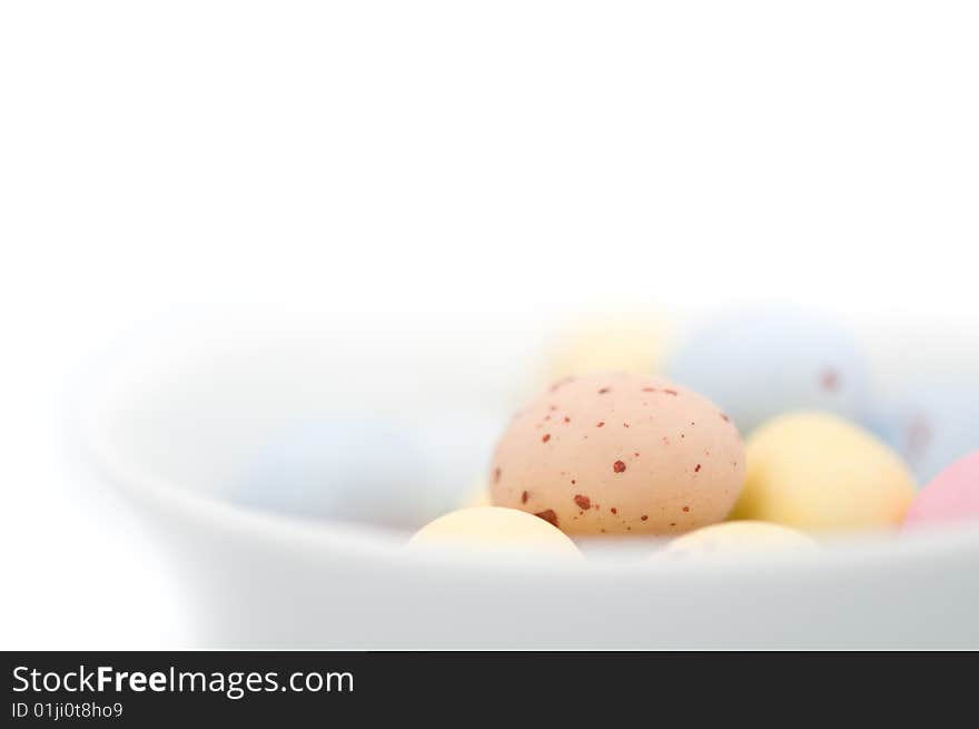 Easter egg chocolate candies on white background and in white bowl. There are some blue, yellow, pink and beige ones. Easter egg chocolate candies on white background and in white bowl. There are some blue, yellow, pink and beige ones.