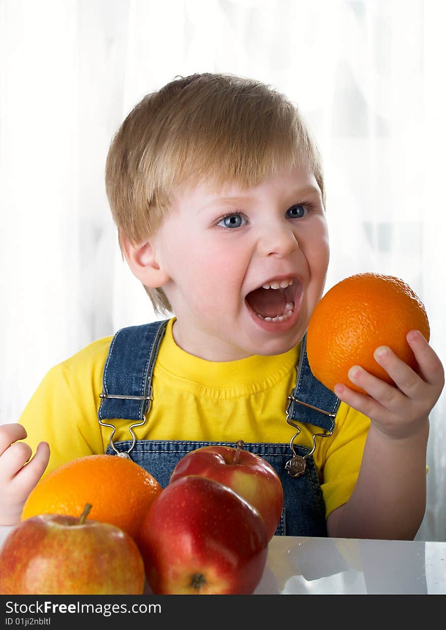 The child sits on a table with fruit. The child sits on a table with fruit