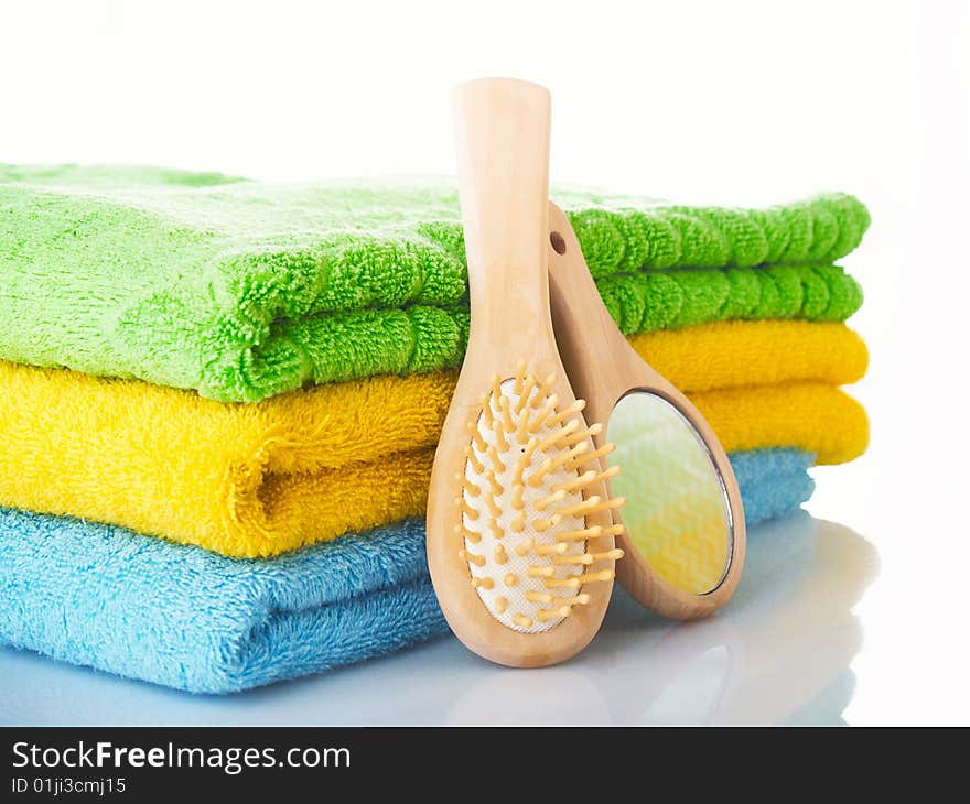 Three terry multi-coloured towels on a table, hairbrush a mirror