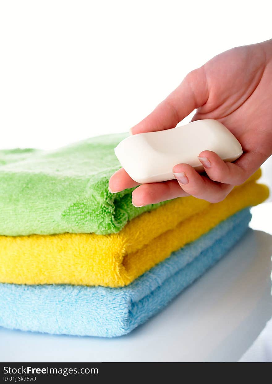 Three terry multi-coloured towels on a table and soap