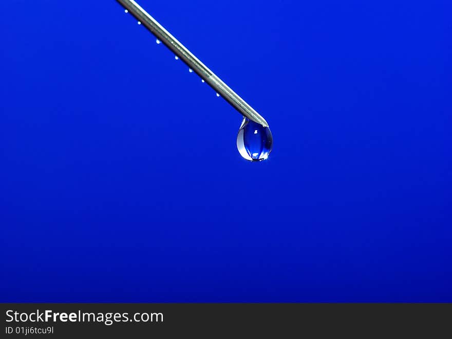 Drop on syringe needle macro on blue