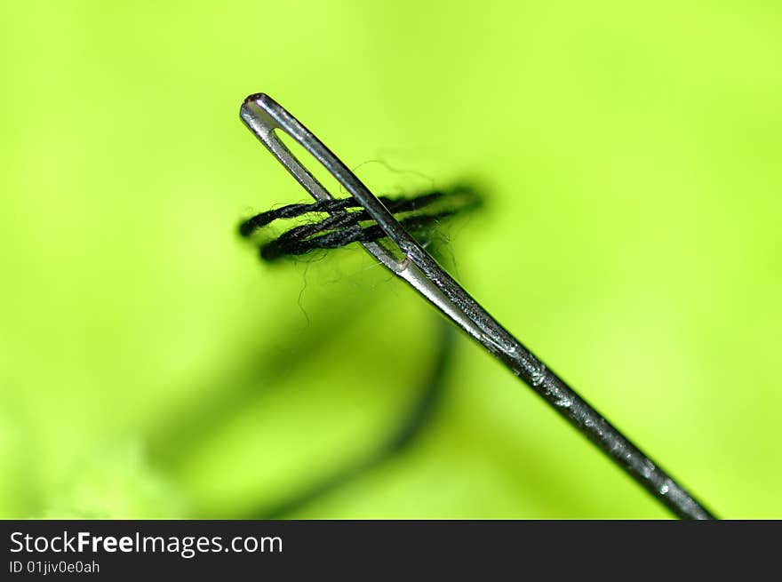 Needle and thread on green background