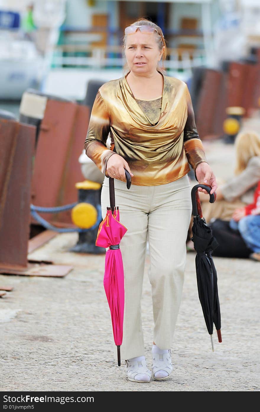 The woman with three umbrellas from a rain goes on a pier in sea port. The woman with three umbrellas from a rain goes on a pier in sea port.