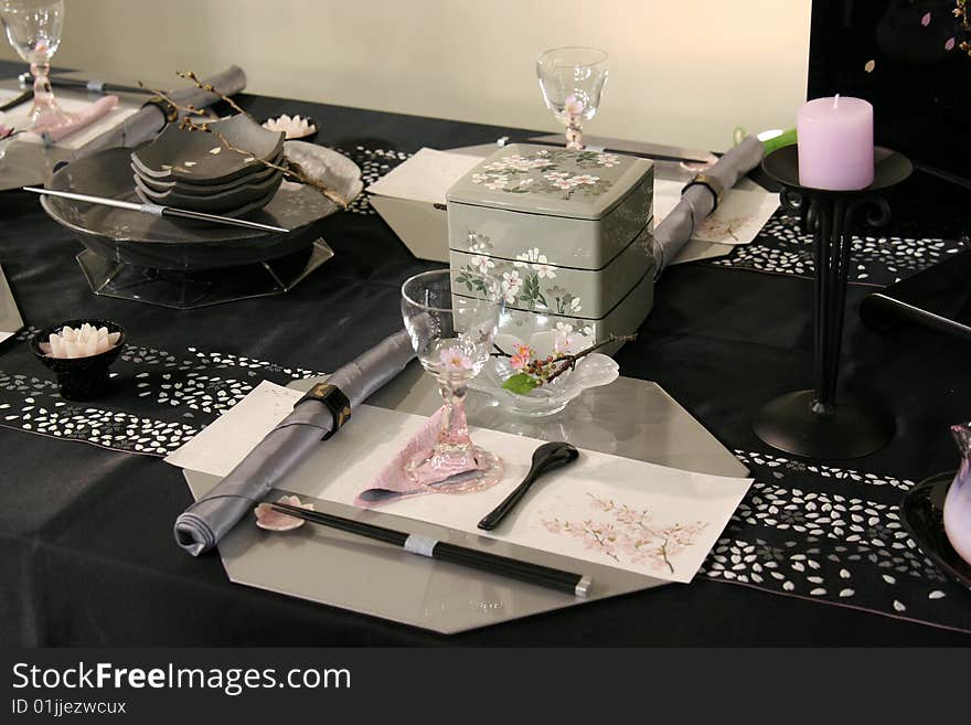 A beautiful table design in Japan.It is consisted of dishes,glasses, towels, a candle with stand and other objects.