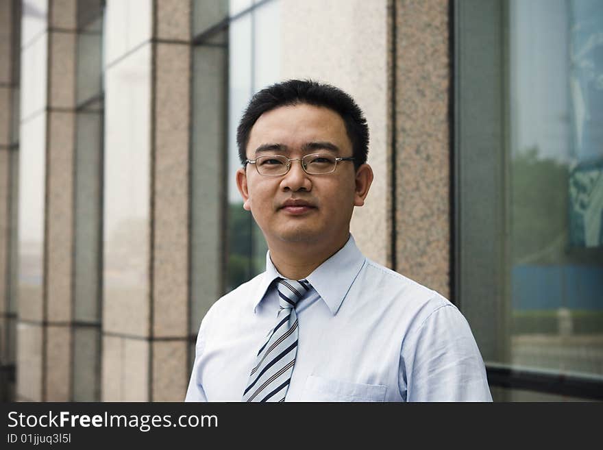 Asian business executive standing in front of office building.