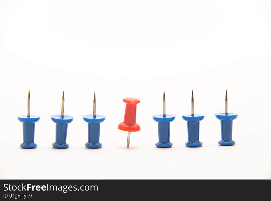 Blue push-pins isolated on white background with a red one pinned down