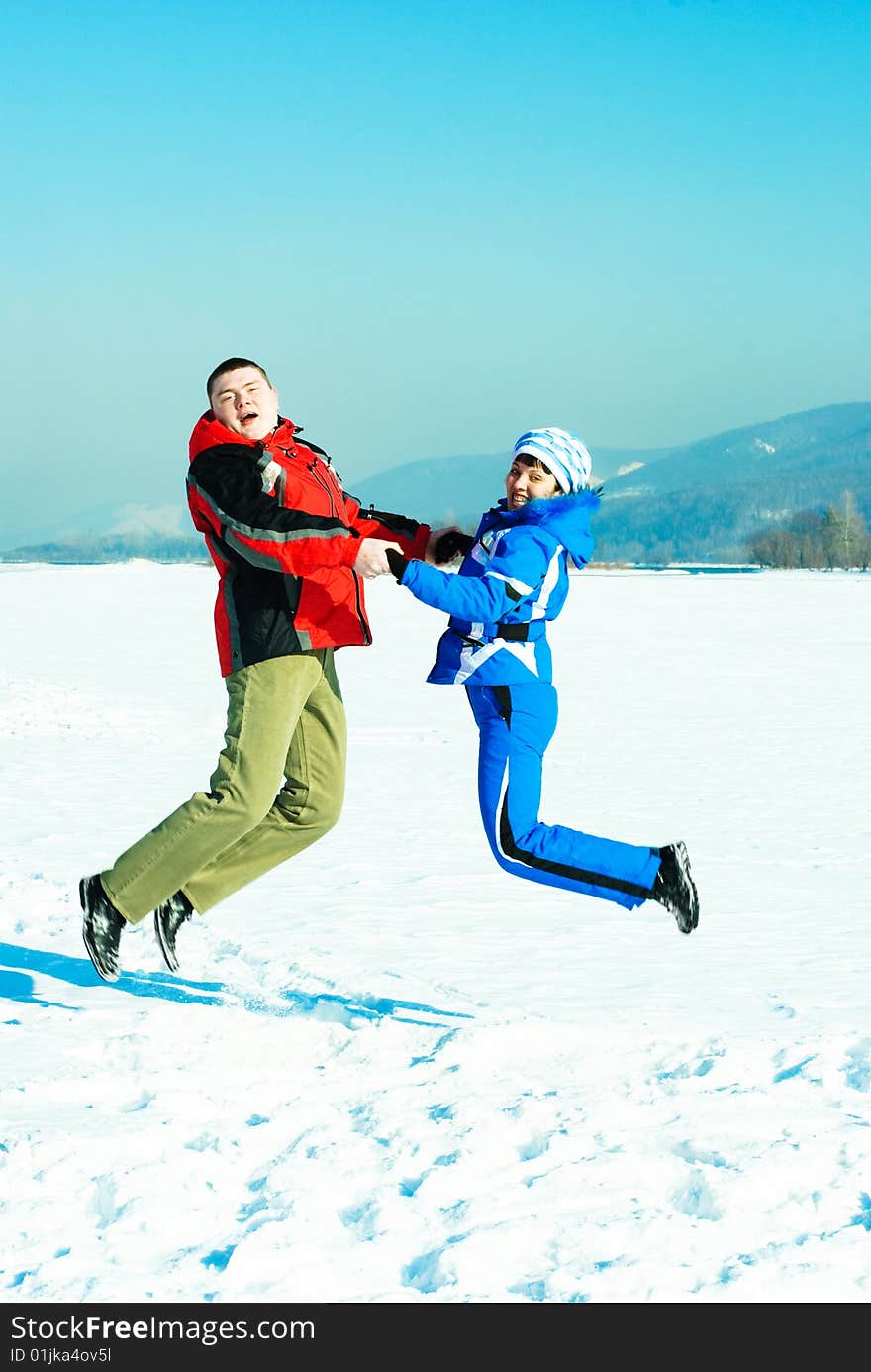 Happy young couple jumping and having fun outdoor in wintertime. Happy young couple jumping and having fun outdoor in wintertime