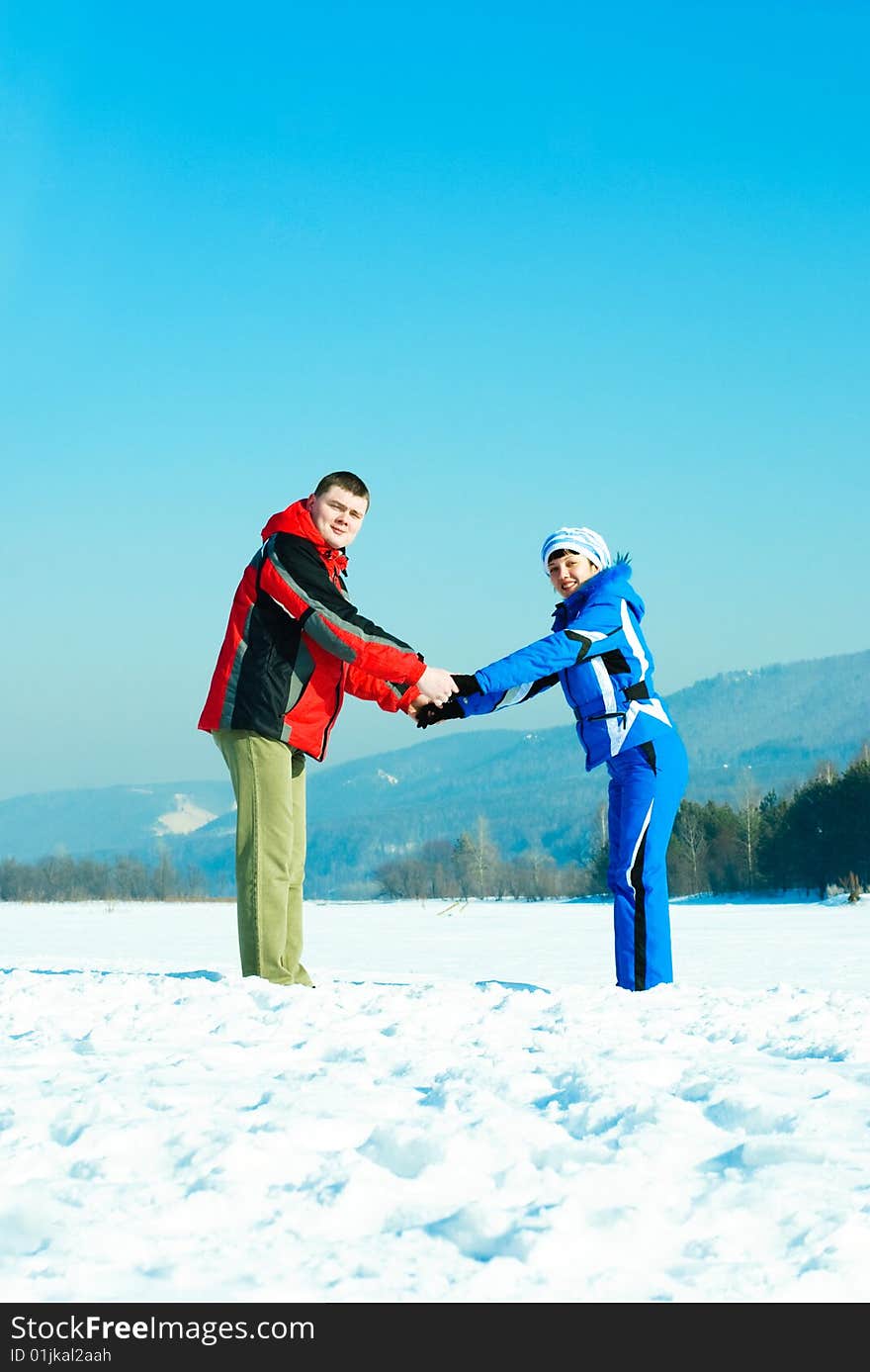 Happy young couple holding hands outdoor in wintertime. Happy young couple holding hands outdoor in wintertime