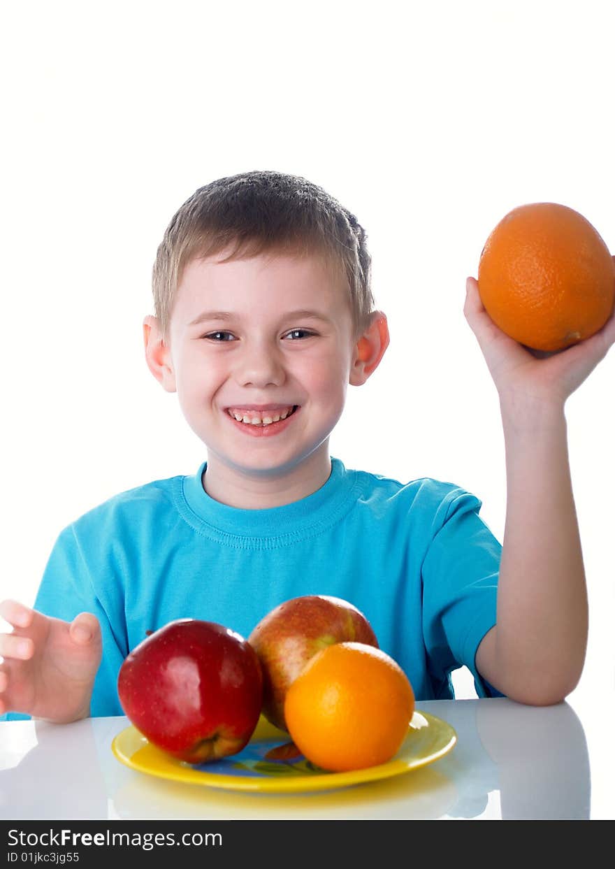 The child sits on a table with fruit. The child sits on a table with fruit