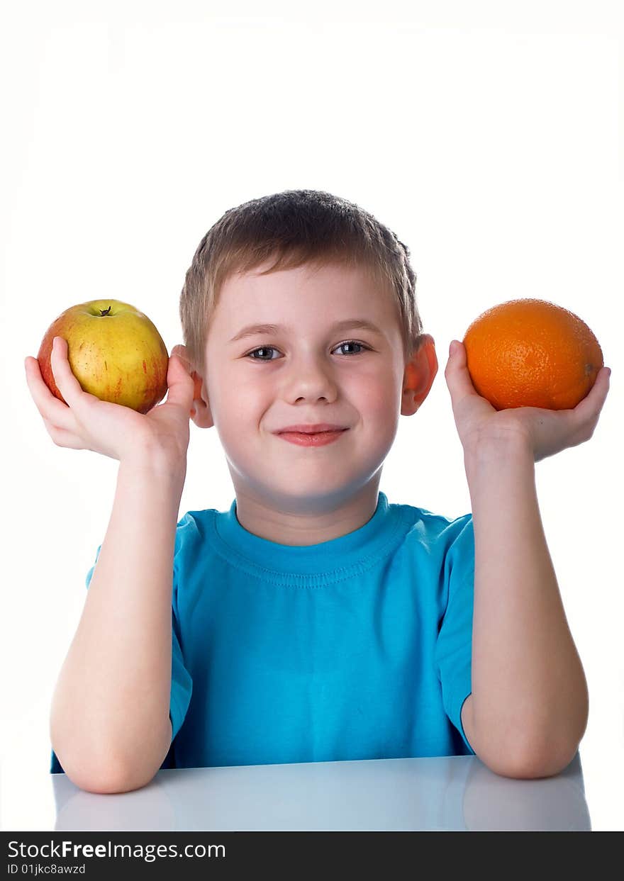 The child sits on a table with fruit. The child sits on a table with fruit