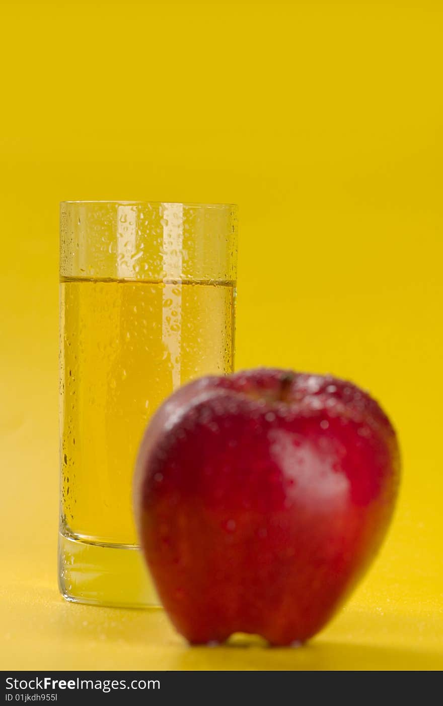 The big red apple and glass of apple juice on a yellow background. The big red apple and glass of apple juice on a yellow background