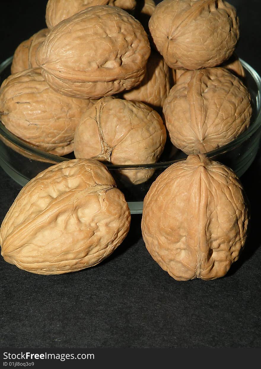 Walnuts in glass plate on black background