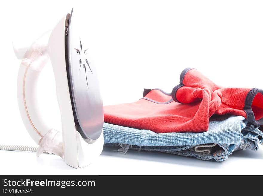 Electric iron and pile of clothes on white background