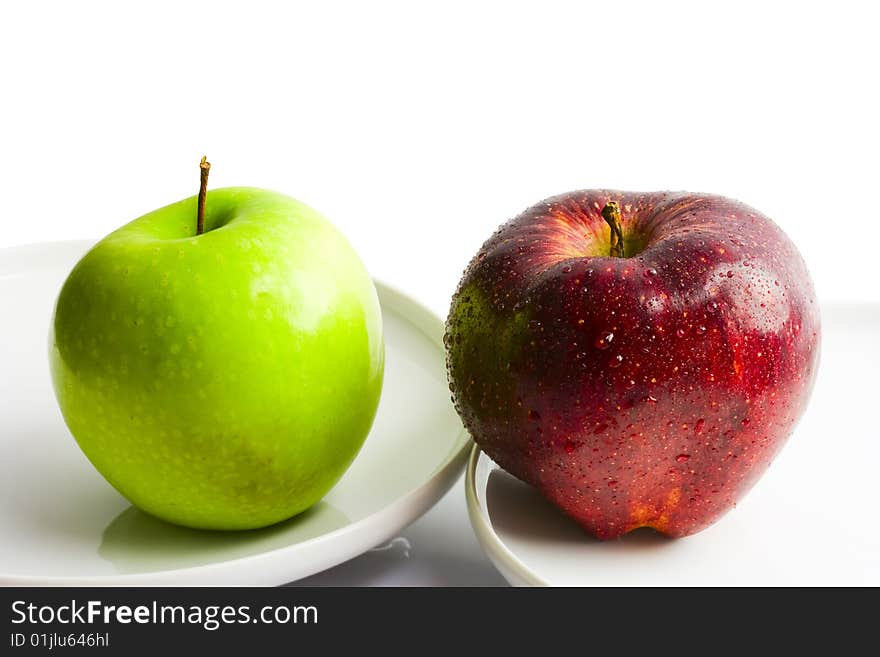 Red and green apple on two white plates. Red and green apple on two white plates