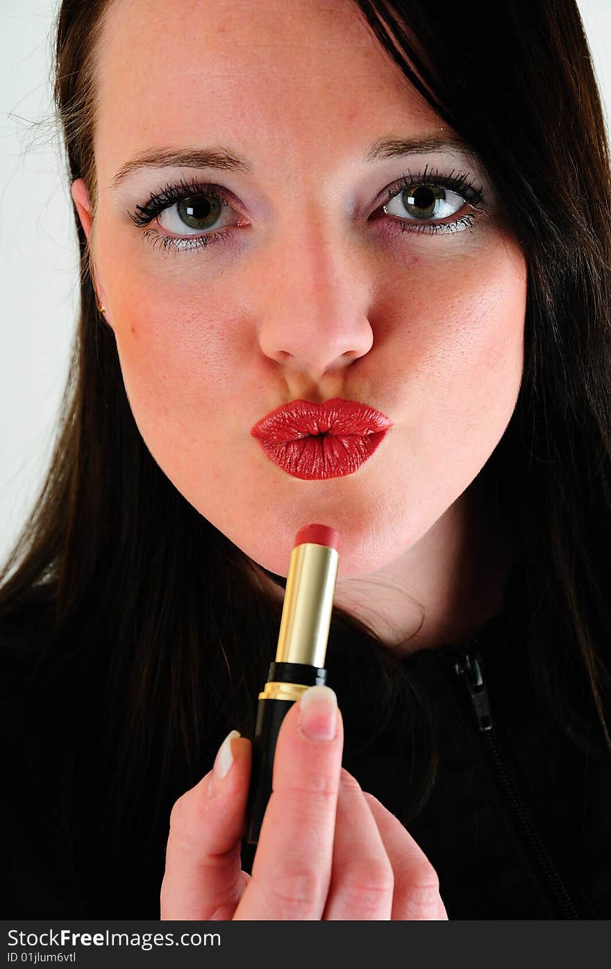 Female model applying lipstick to her lip then pullinga facial expression that seems to be blowing a kiss or pouting