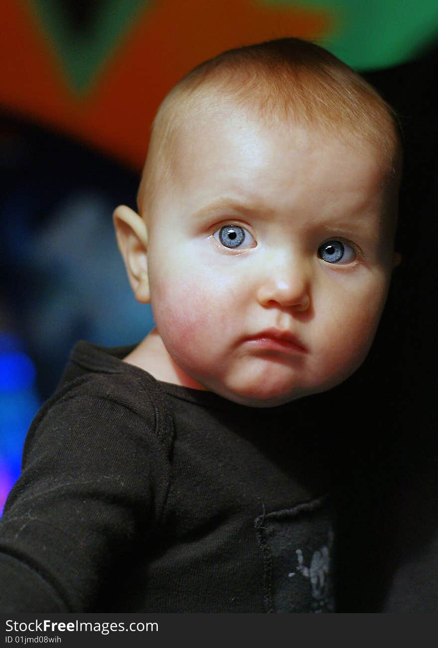 Portrait of a blue-eyed baby girl with red hair against a colourful background. Portrait of a blue-eyed baby girl with red hair against a colourful background