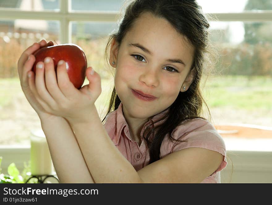 Brown haired child presenting an apple. Healthy lifstyle image.