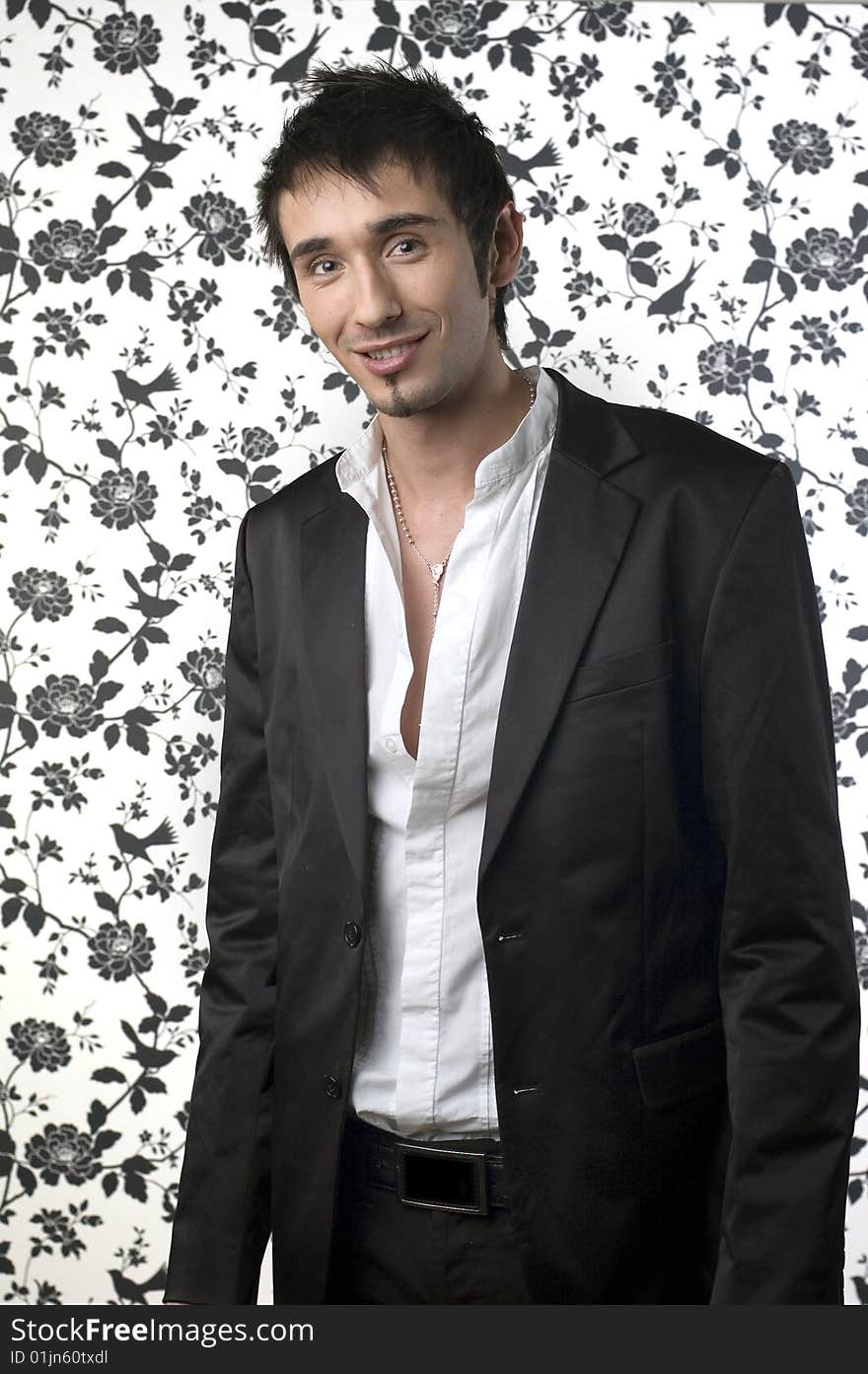 Young handsome man posing in black suit in front of a flower background. Young handsome man posing in black suit in front of a flower background