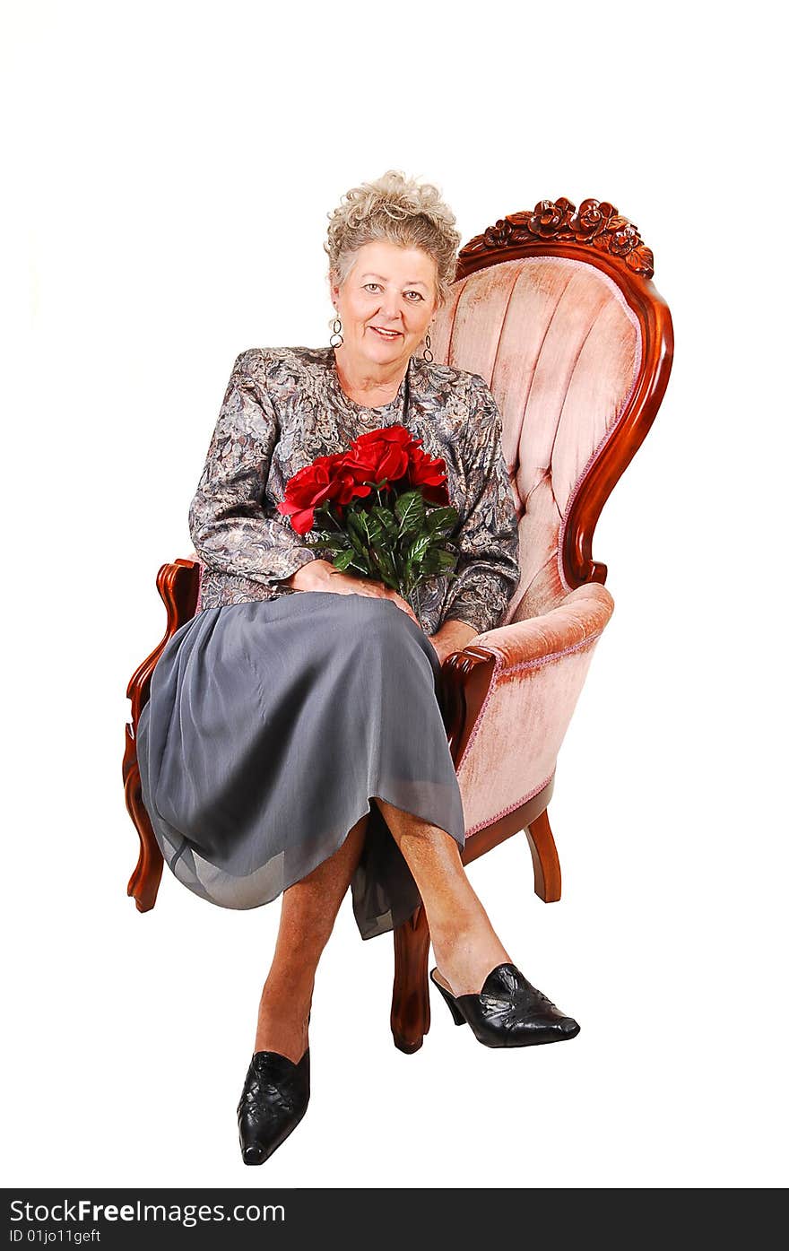 All dressed up elderly woman with red roses in her hand, for her 60th birdsday. Sitting in a pink armchair for white background. All dressed up elderly woman with red roses in her hand, for her 60th birdsday. Sitting in a pink armchair for white background.