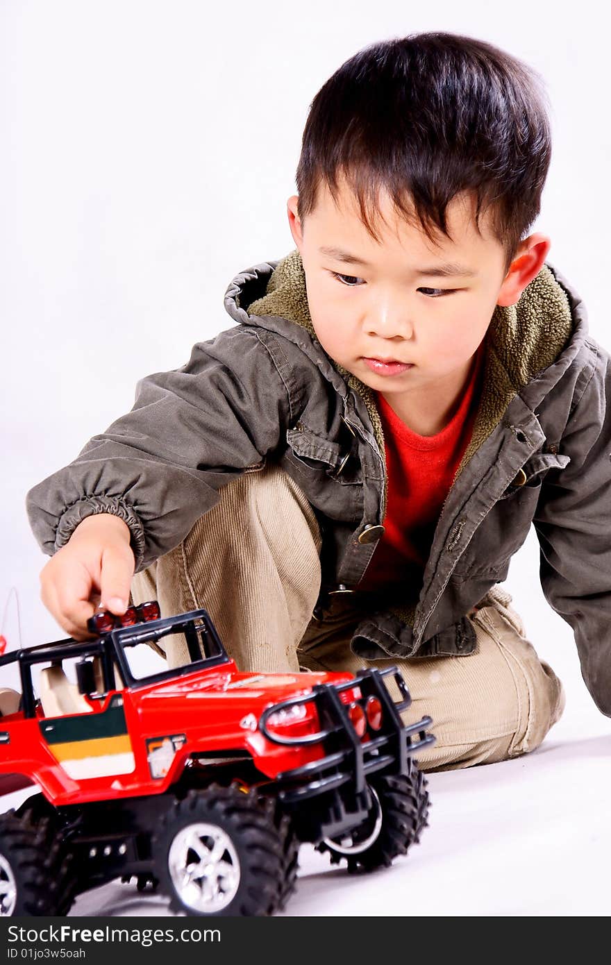 A picture of a little chinese boy looking attentively at a remote control car, smiling. A picture of a little chinese boy looking attentively at a remote control car, smiling