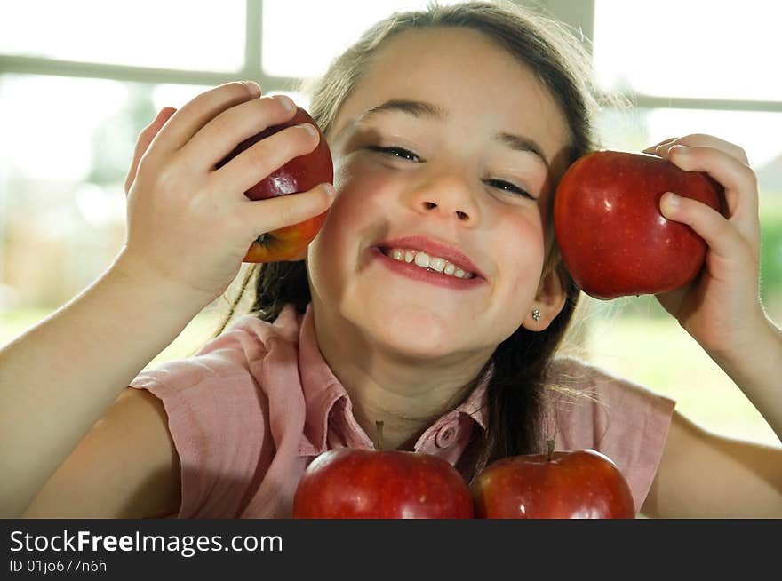 Brown haired child playing with apples. Healthy lifstyle image.