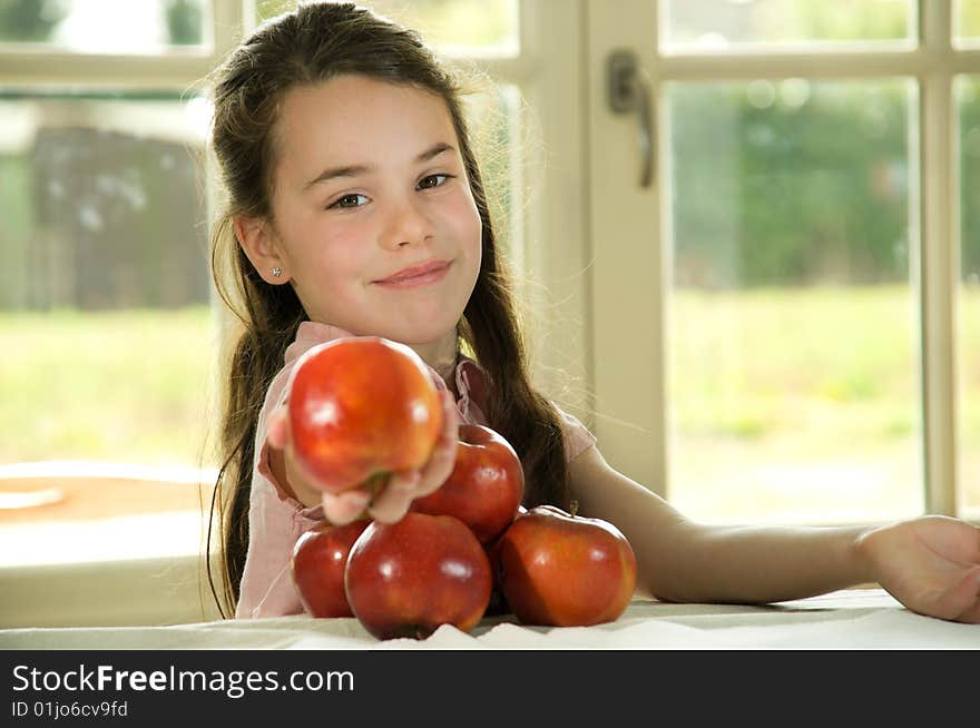 Brown haired child presenting an apple. Healthy lifstyle image.