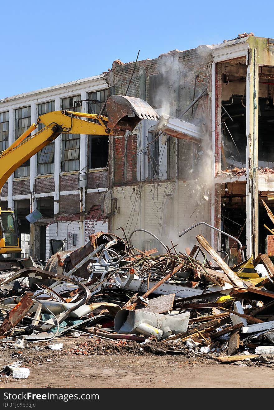 An excavator demolishing a two story concrete building. An excavator demolishing a two story concrete building