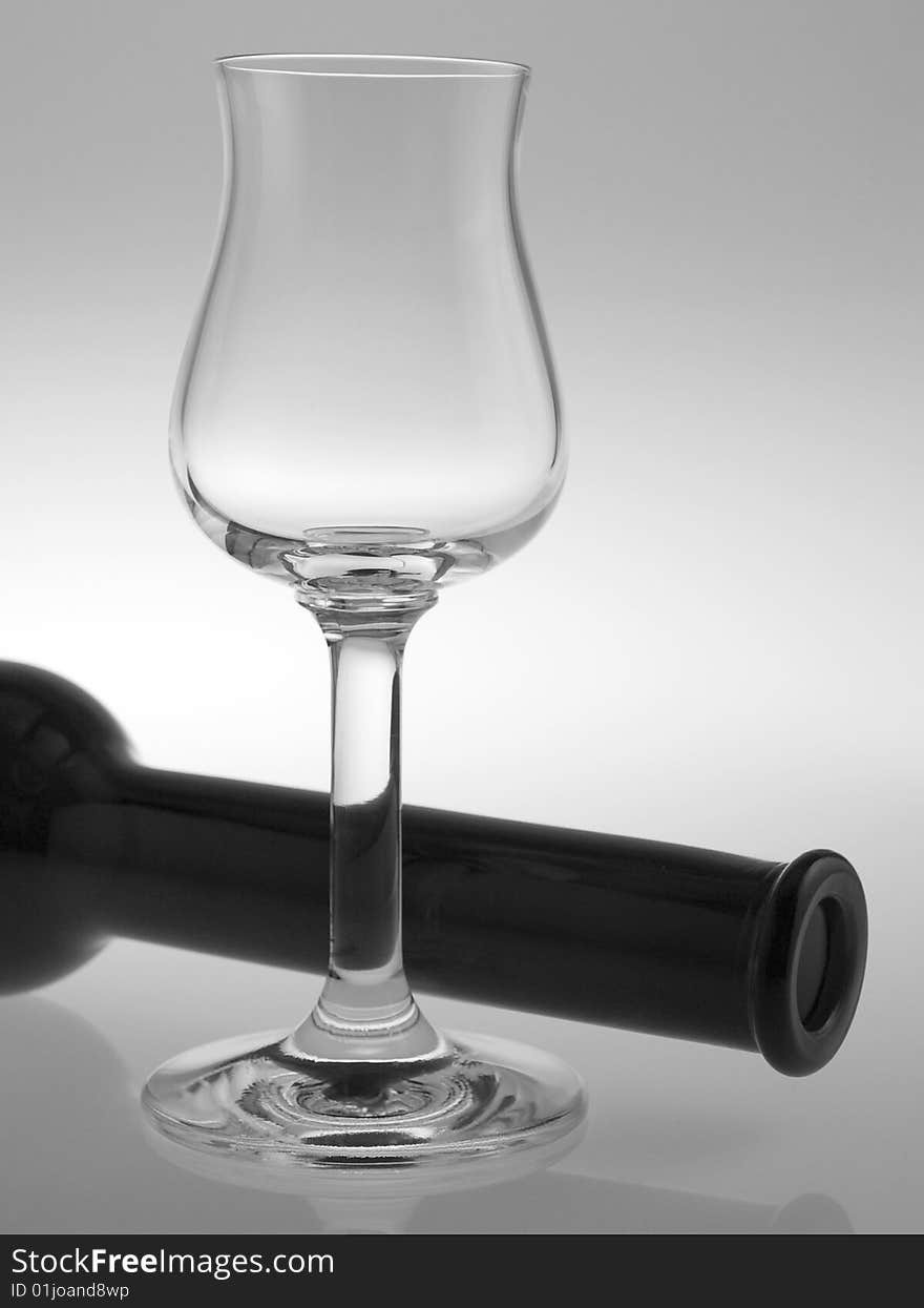 A liqueur glass with bottle on reflective background