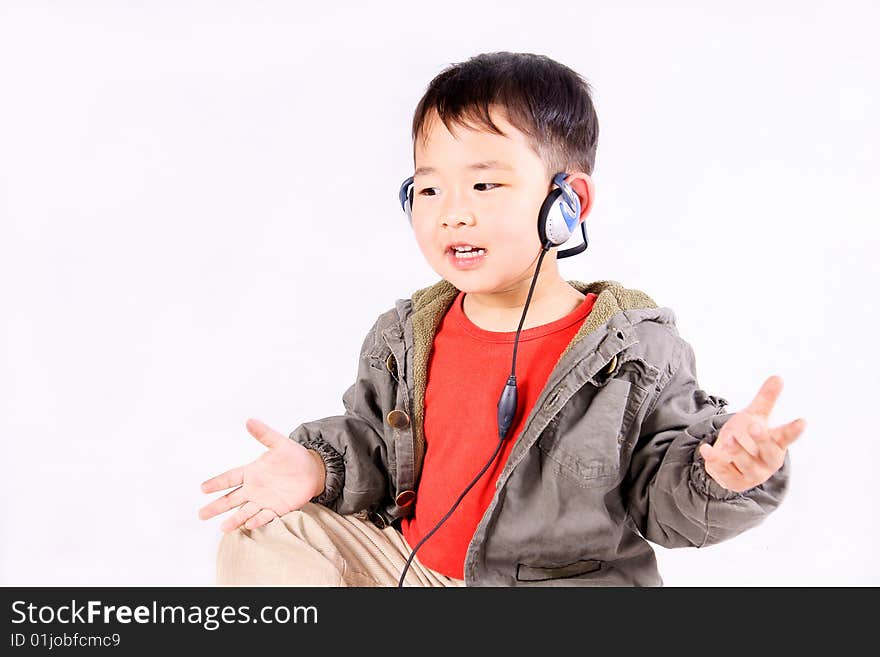 A picture of a little chinese boy listening to music with earphone, having great fun. A picture of a little chinese boy listening to music with earphone, having great fun