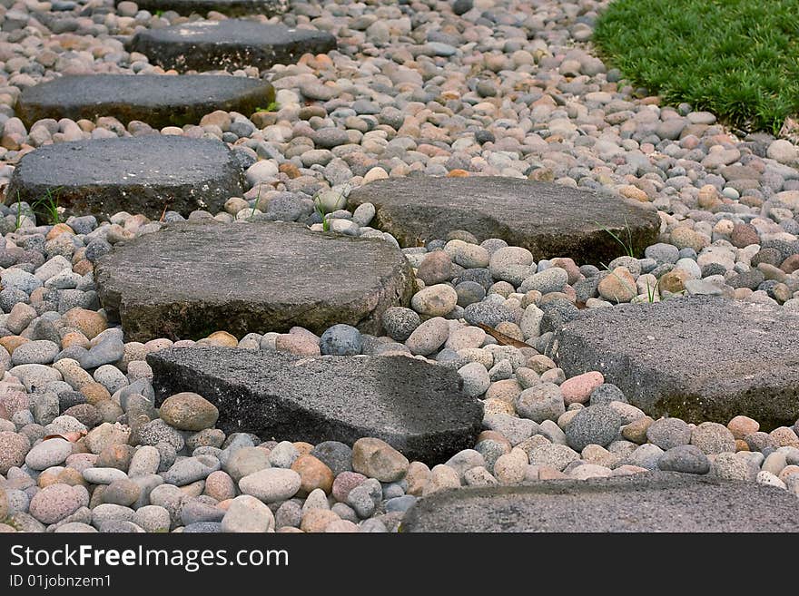 Walkway of stone slabs among the dead pebbles and living grass. Walkway of stone slabs among the dead pebbles and living grass