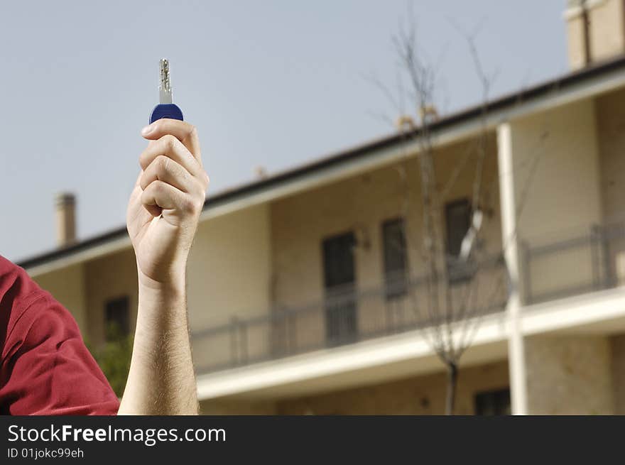 Young man and new home; young man looking new home with door key in hand; concept of real estate. Young man and new home; young man looking new home with door key in hand; concept of real estate