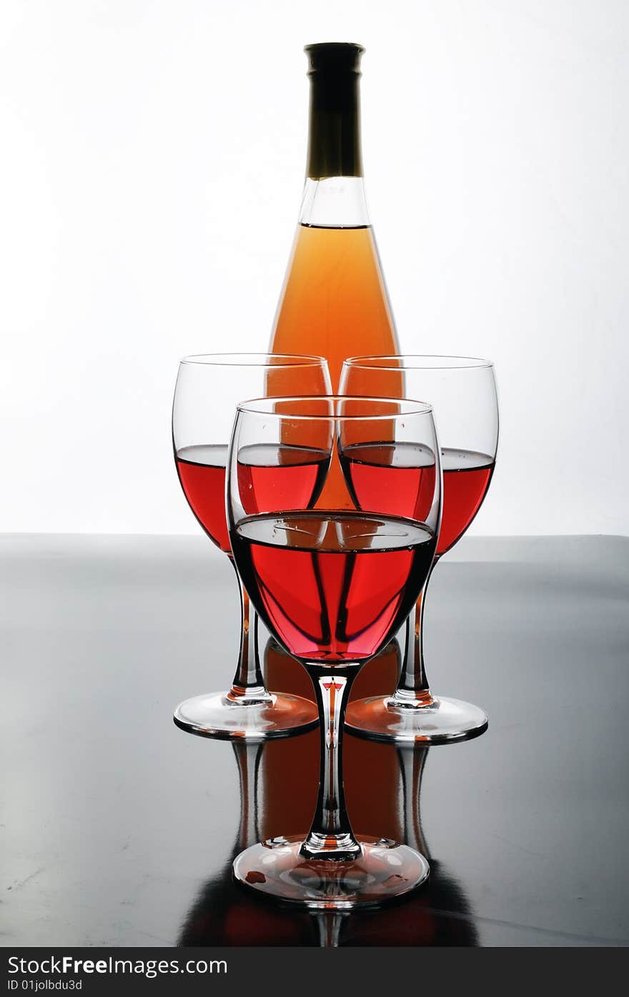 Bottle and glasses of wine on white background with reflections