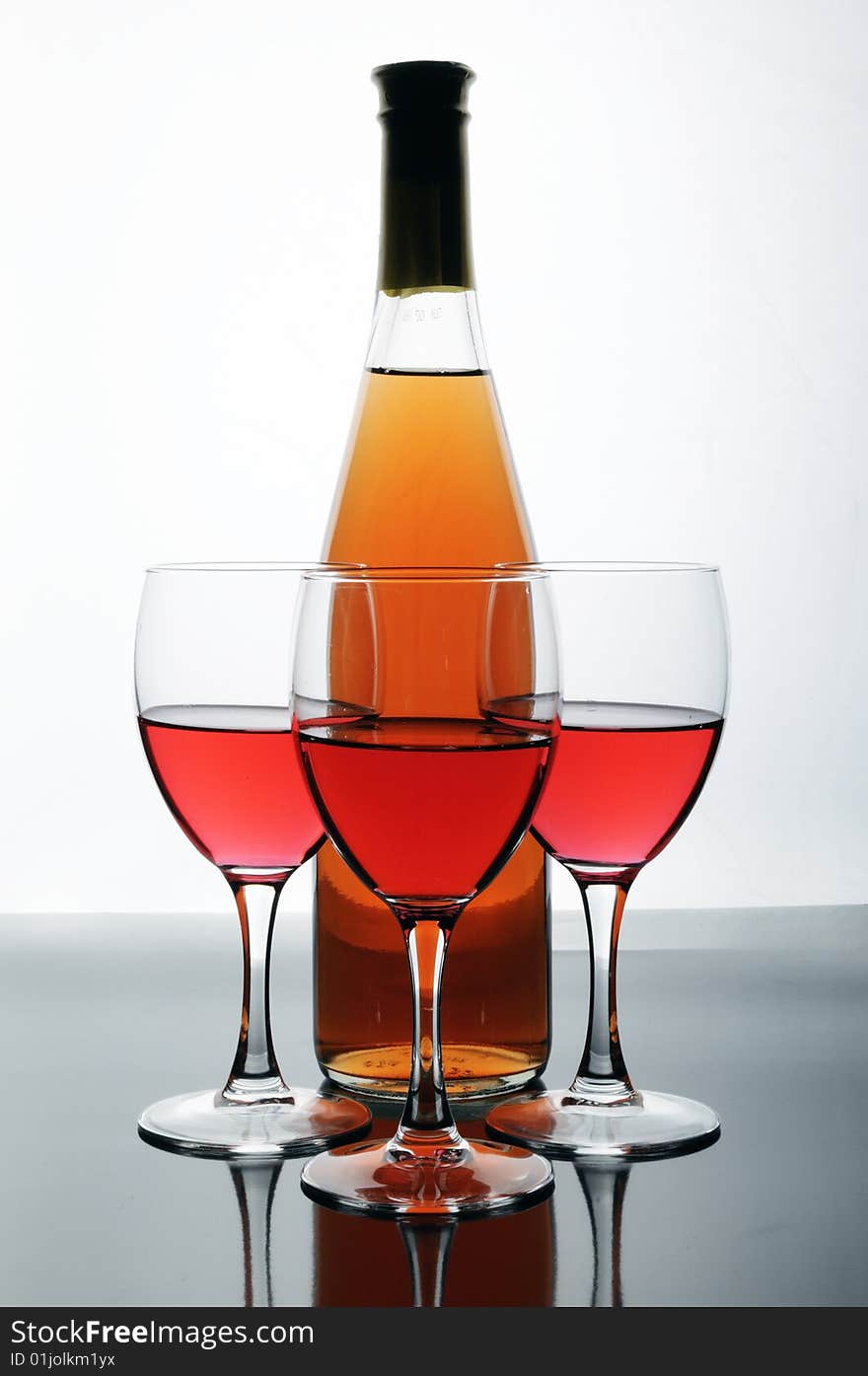 Bottle and glasses of wine on white background with reflections