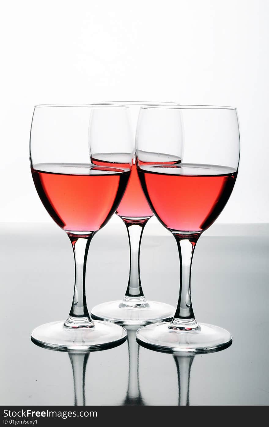 Bottle and glasses of wine on white background with reflections