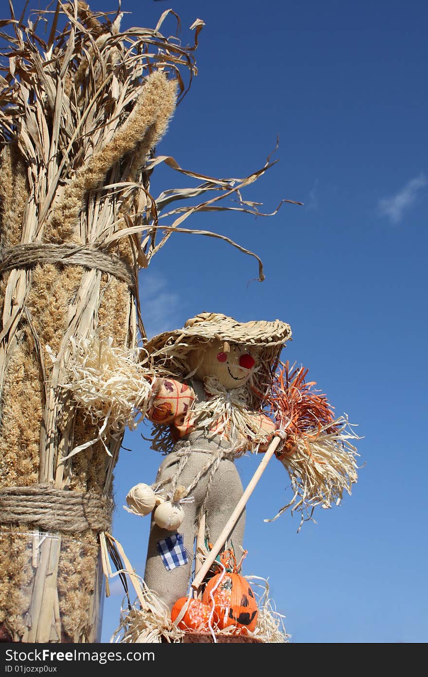 Sun is shining and the scarecrow is standing by some oats and hay. Sun is shining and the scarecrow is standing by some oats and hay